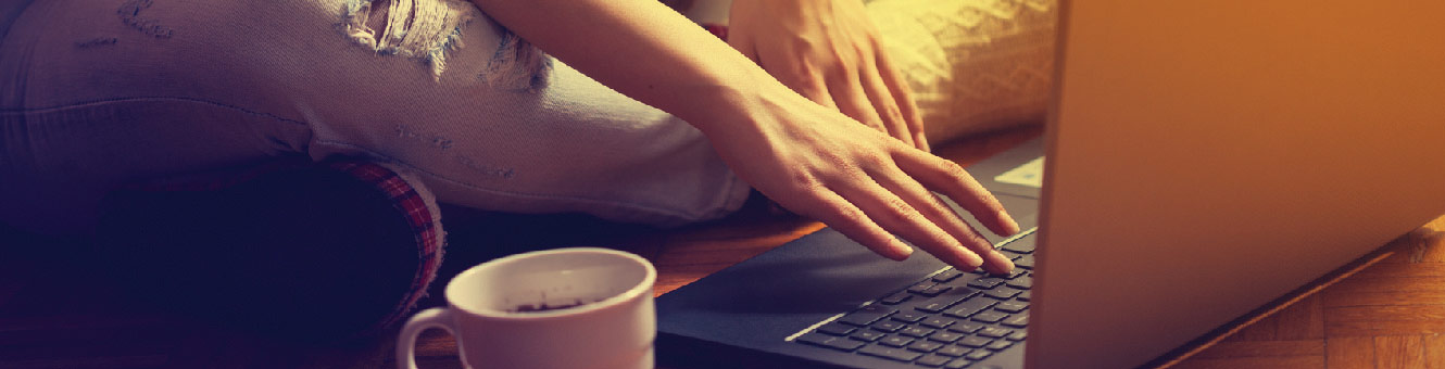 Young woman sitting in the floor banking on her laptop.