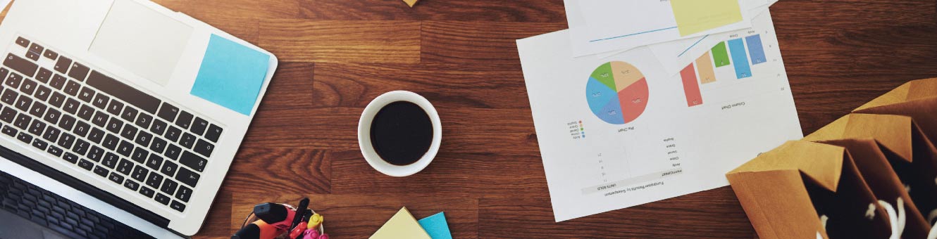 Laptop on a table with a cup of coffee and a sales graph.