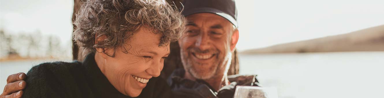 Retired couple smiling and relaxing outdoors.