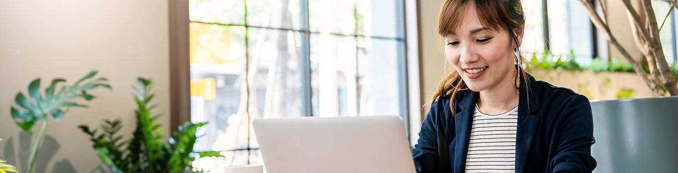 Woman using laptop in room with plants.